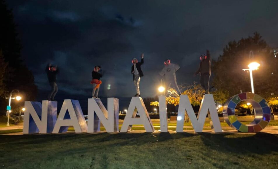 Photo of a group at Maffeo Sutton Park, atop the Nanaimo sign